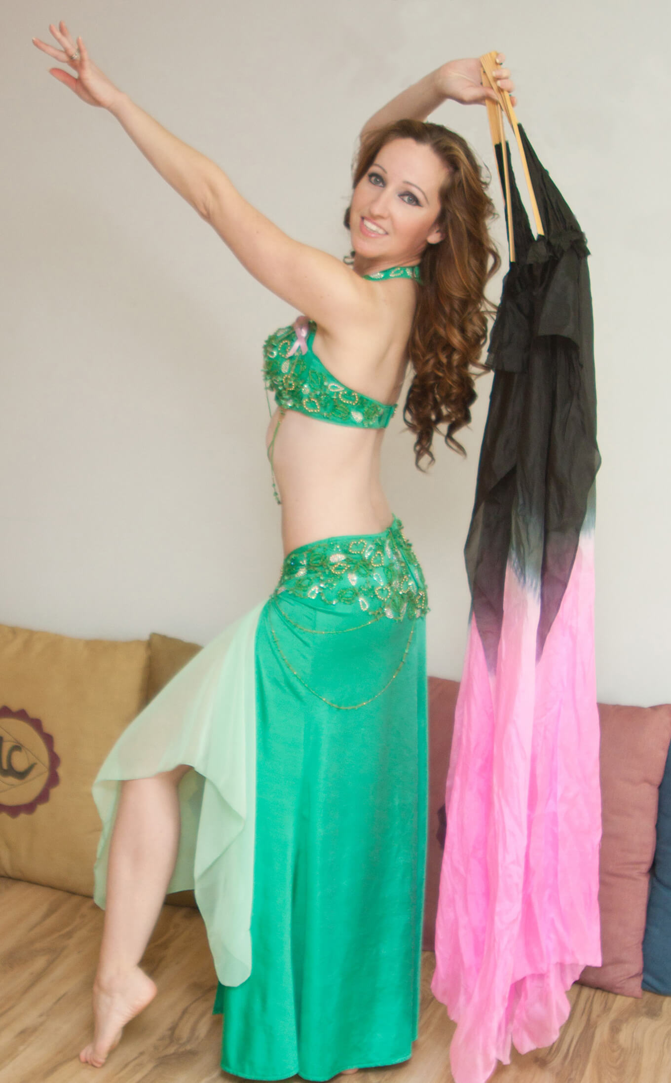 Donna wearing a green belly dance outfit with a fan
