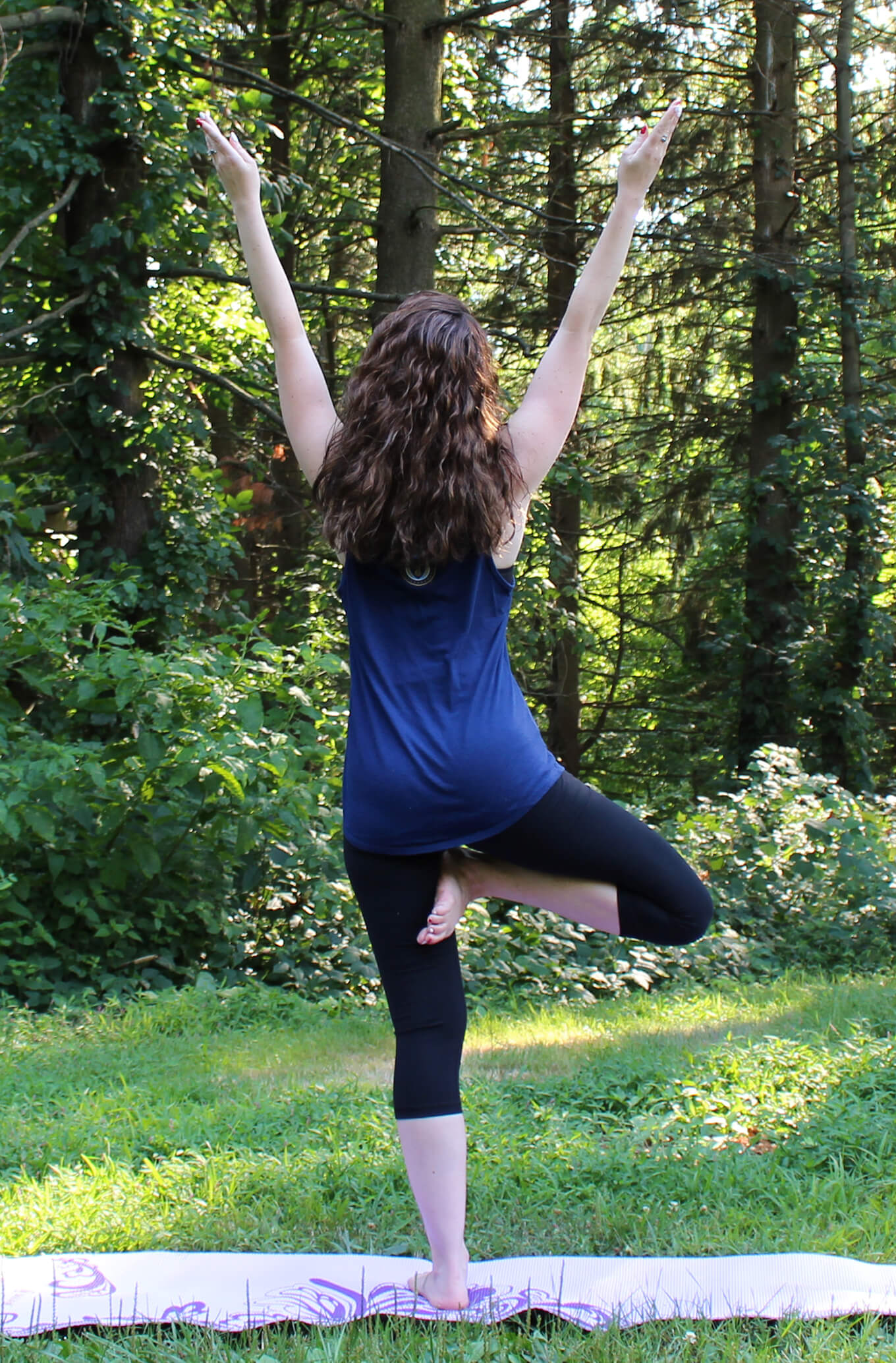 Donna demonstrating a tree yoga pose while outside